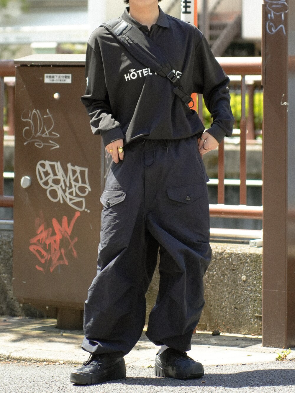 ブラック系のポロシャツ、ブラック系のショルダーバッグ、ブラック系のカーゴパンツを着用したメンズの春コーディネートの5枚目の写真