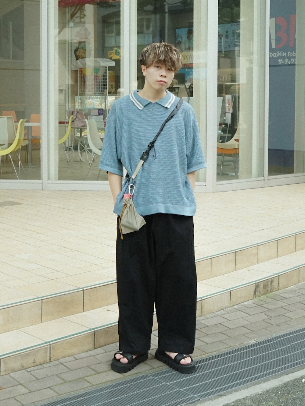 ブルー系のポロシャツ、ベージュ系のショルダーバッグ、ブラック系のサンダルを着用したメンズの夏コーディネートの2枚目の写真
