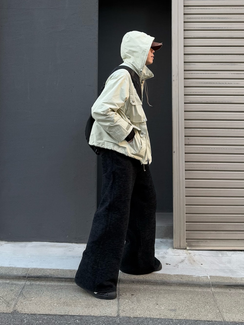 ブラック系のショルダーバッグ、ブラック系のスニーカー、ベージュ系のマウンテンパーカーを着用したメンズの冬コーディネートの2枚目の写真