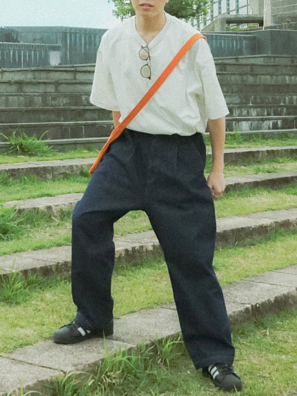 ホワイト系のTシャツ/カットソー、ブルー系のデニムパンツ、オレンジ系のショルダーバッグを着用したメンズの春コーディネートの5枚目の写真