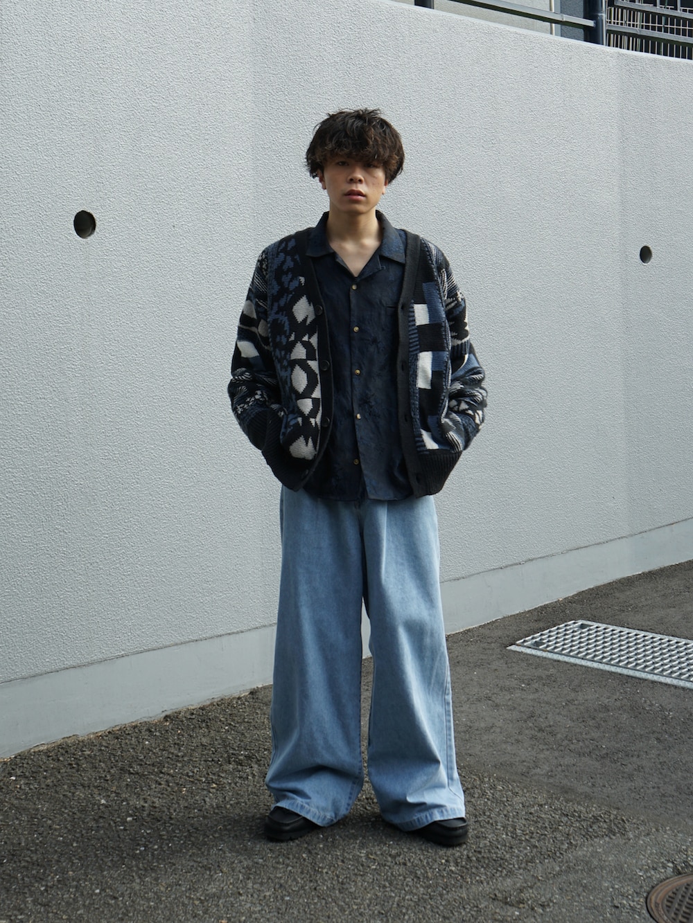 ブルー系のカーディガン/ボレロ、ブルー系のスラックス、ブラック系のブーツを着用したメンズの秋コーディネートの2枚目の写真