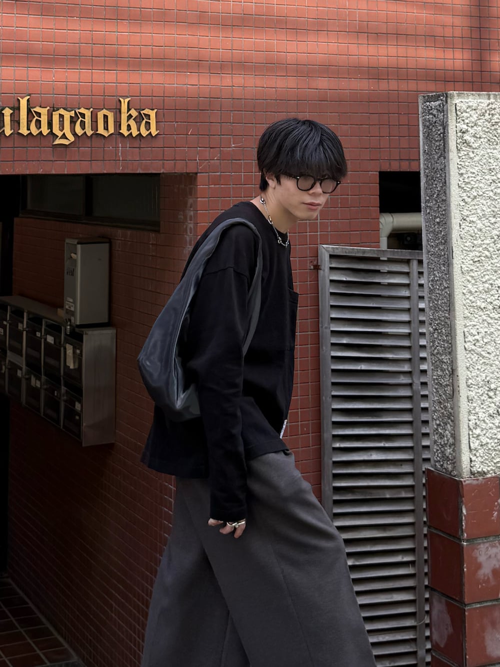 ブラック系のTシャツ/カットソー、ブラウン系のスラックス、グレー系のハンドバッグを着用したメンズの秋コーディネートの3枚目の写真