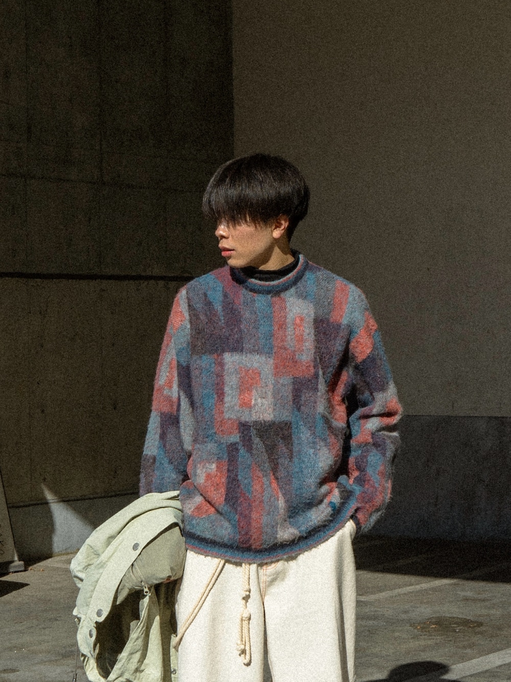 ブルー系のニット/セーター、ベージュ系のマウンテンパーカー、ブラック系のデニムパンツを着用したメンズの冬コーディネートの3枚目の写真