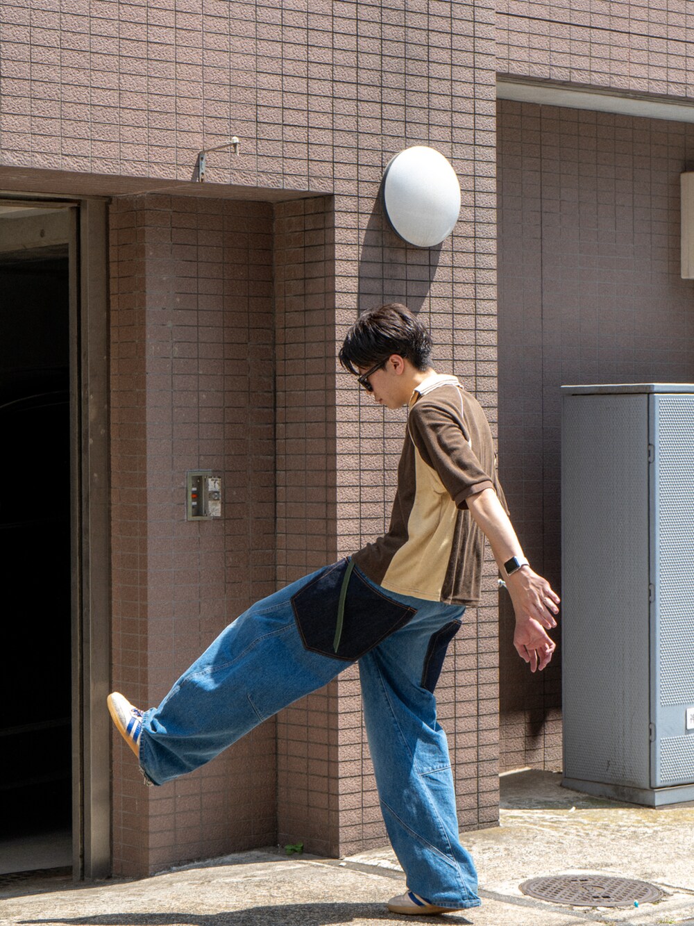 ブラウン系のポロシャツ、ブルー系のデニムパンツ、ホワイト系のスニーカーを着用したメンズの夏コーディネートの3枚目の写真