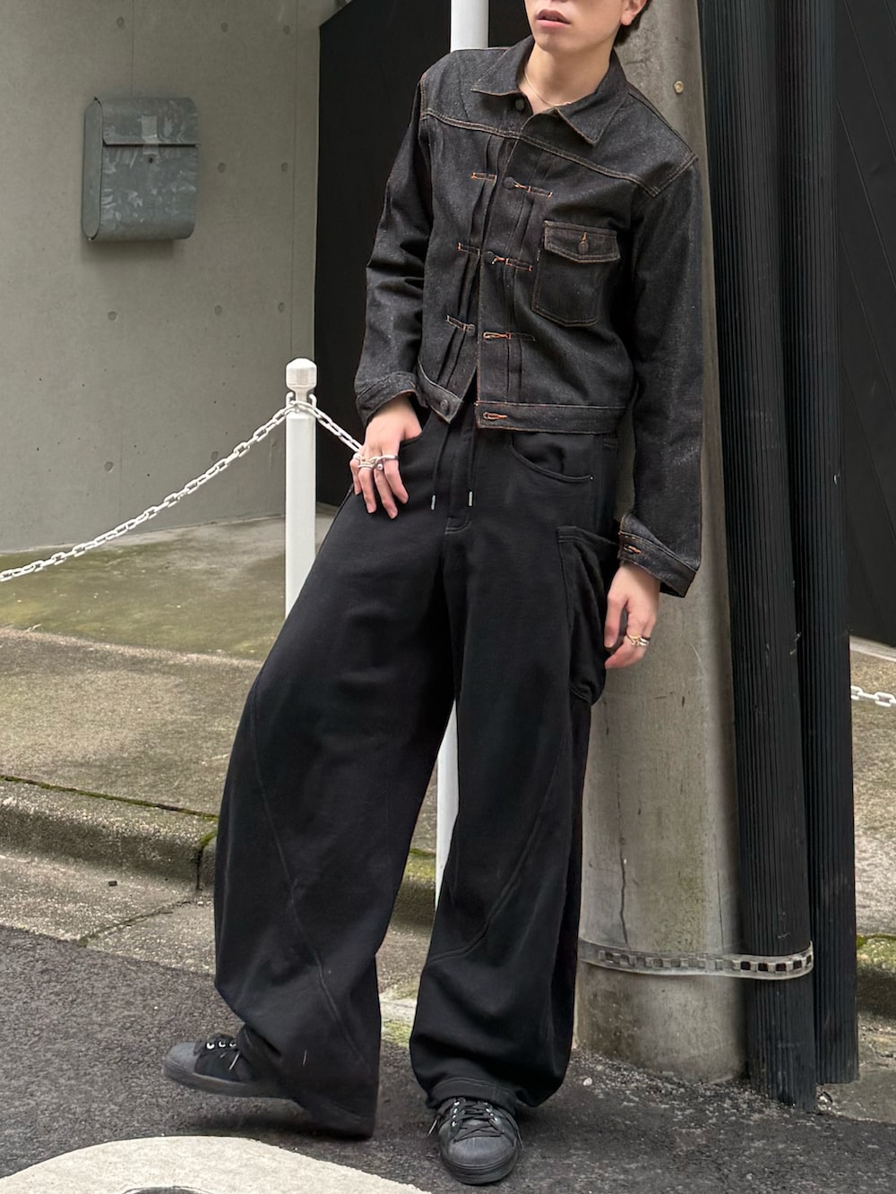 ブラック系のデニムジャケット、ブラック系のスウェットパンツ、ブラック系のスニーカーを着用したメンズの秋コーディネートの4枚目の写真
