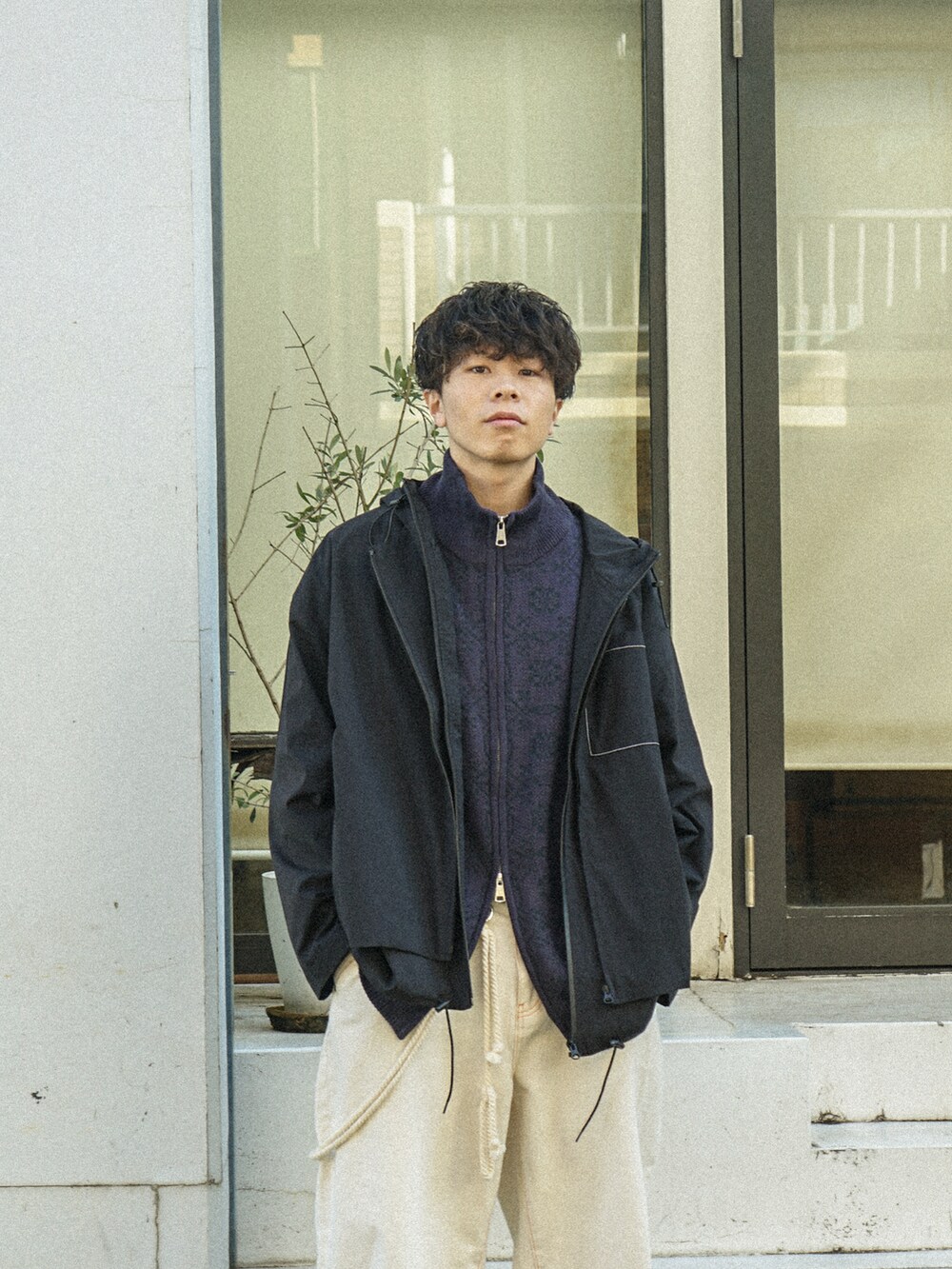 ブラック系のマウンテンパーカー、パープル系のニット/セーター、ブラック系のデニムパンツを着用したメンズの冬コーディネートの4枚目の写真