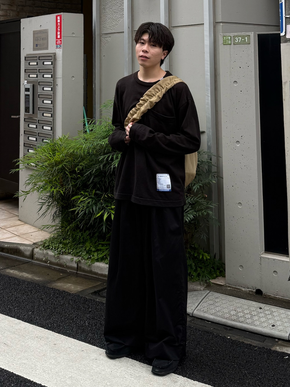 ブラック系のTシャツ/カットソー、ブラック系のその他パンツ、ベージュ系のショルダーバッグを着用したメンズの春コーディネートの2枚目の写真