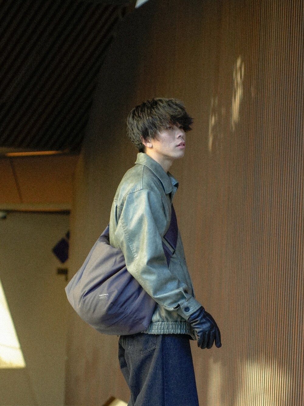 グレー系のブルゾン、ブラック系のデニムパンツ、グレー系のショルダーバッグを着用したメンズの冬コーディネートの4枚目の写真