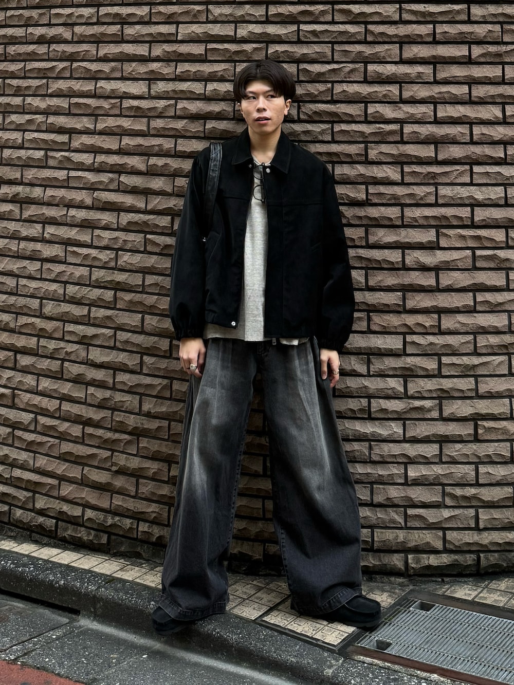 ブラック系のブルゾン、グレー系のTシャツ/カットソー、ブラック系のデニムパンツを着用したメンズの秋コーディネートの2枚目の写真