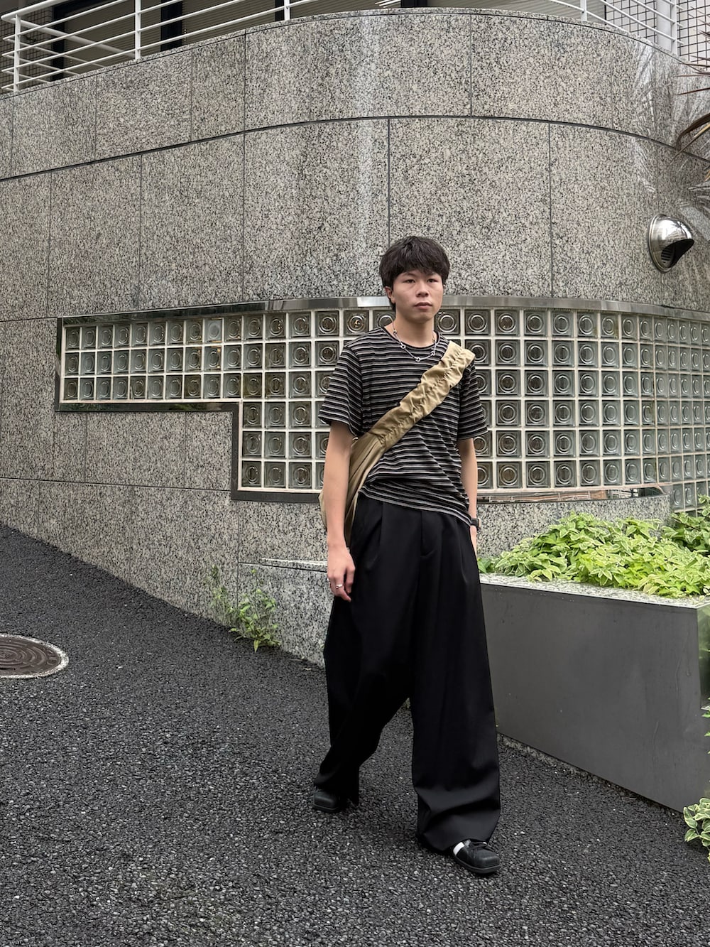 ブラック系のTシャツ/カットソー、ブラック系のスラックス、ベージュ系のショルダーバッグを着用したメンズの夏コーディネートの3枚目の写真