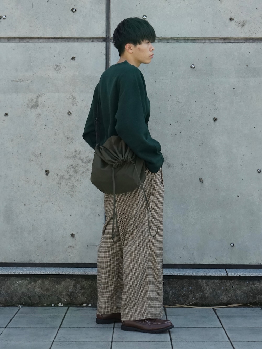 グリーン系のニット/セーター、ベージュ系のスラックス、ブラウン系のモカシン/デッキシューズを着用したメンズの秋コーディネートの2枚目の写真