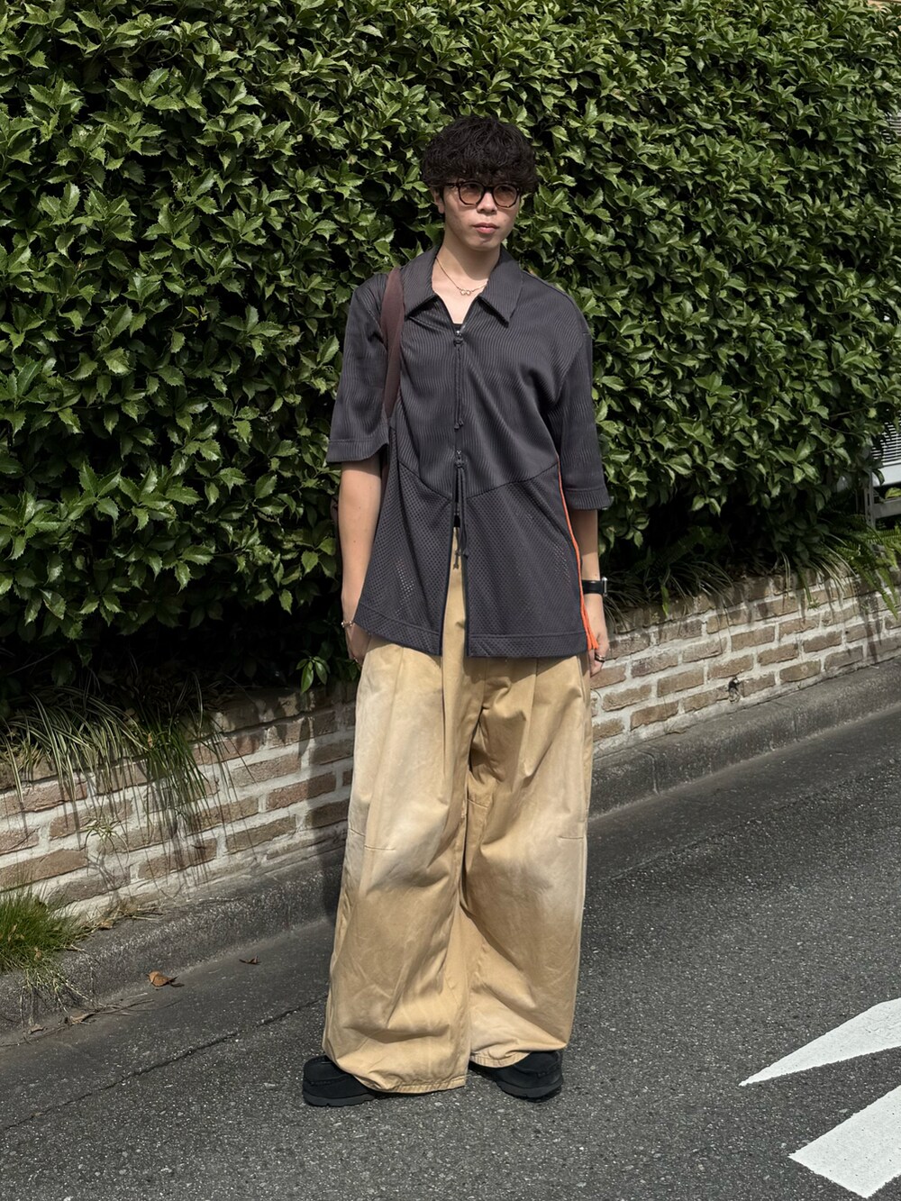 ベージュ系のチノパンツ、ブラウン系のトートバッグ、グレー系のトップスを着用したメンズの夏コーディネートの2枚目の写真