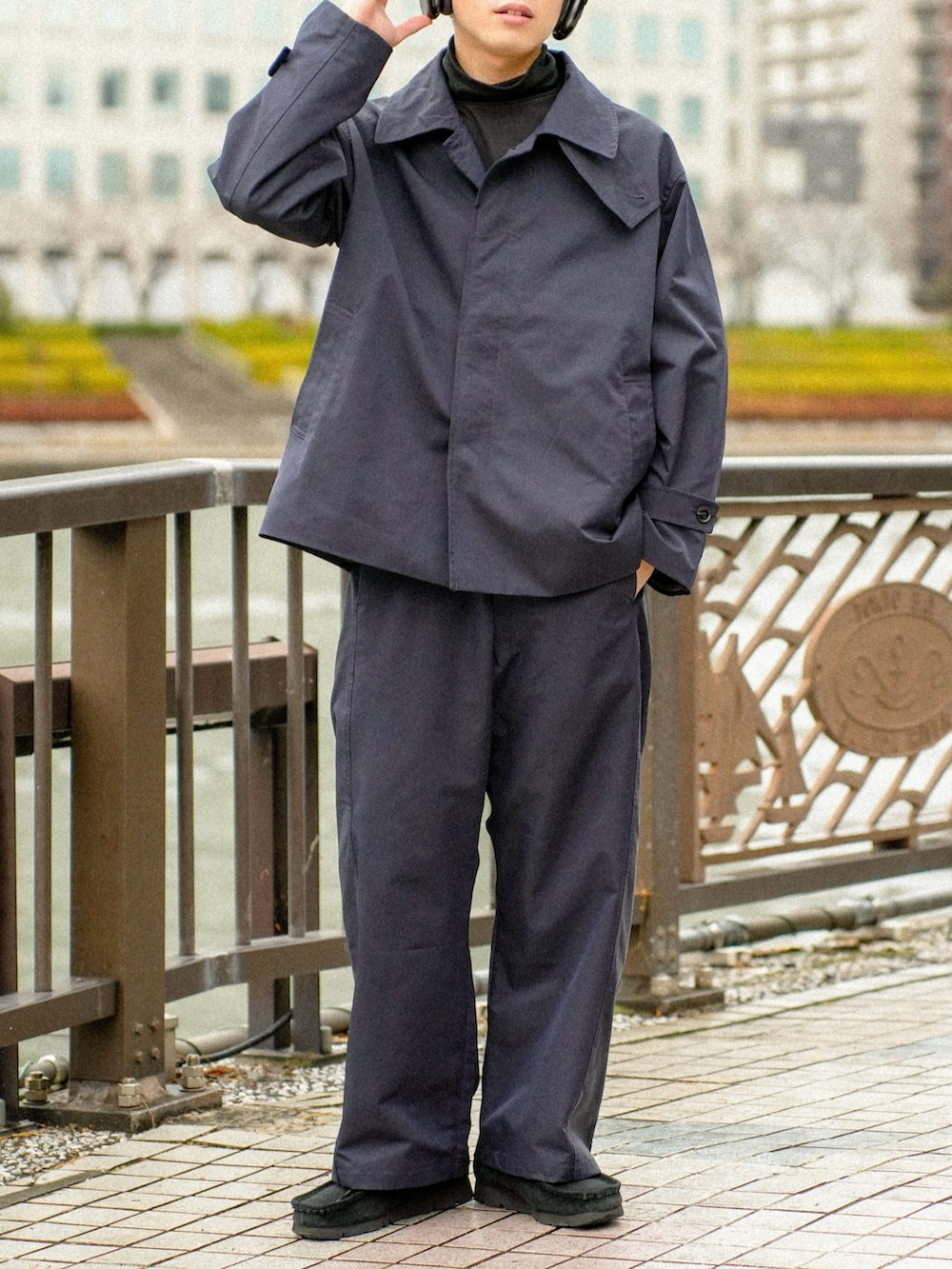 ブラック系のステンカラーコート、ブラック系のその他パンツ、ブラック系のその他シューズを着用したメンズの冬コーディネートの4枚目の写真