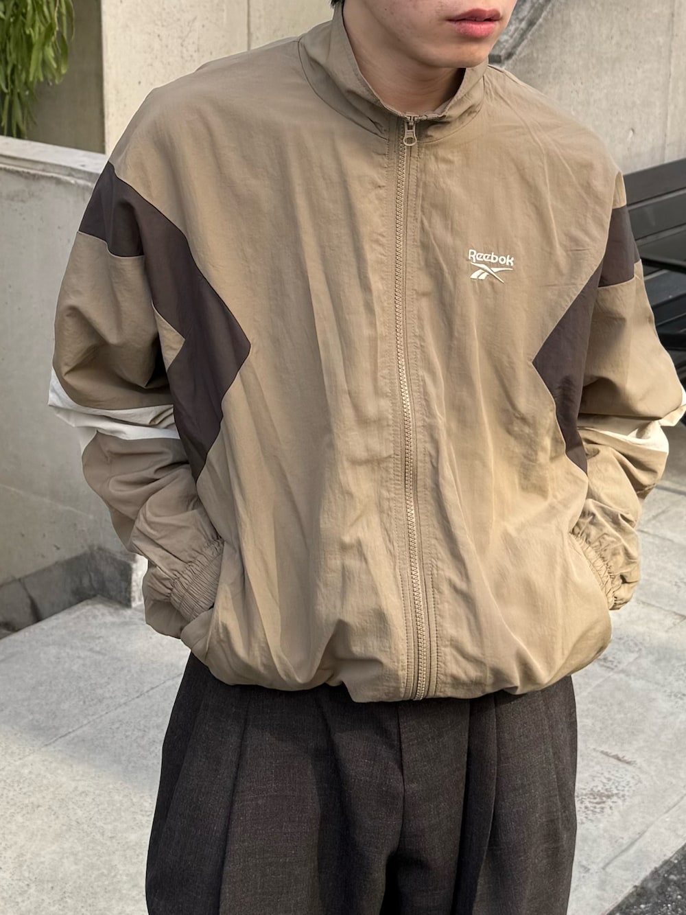 ベージュ系のナイロンジャケットを着用したメンズの春コーディネートの2枚目の写真