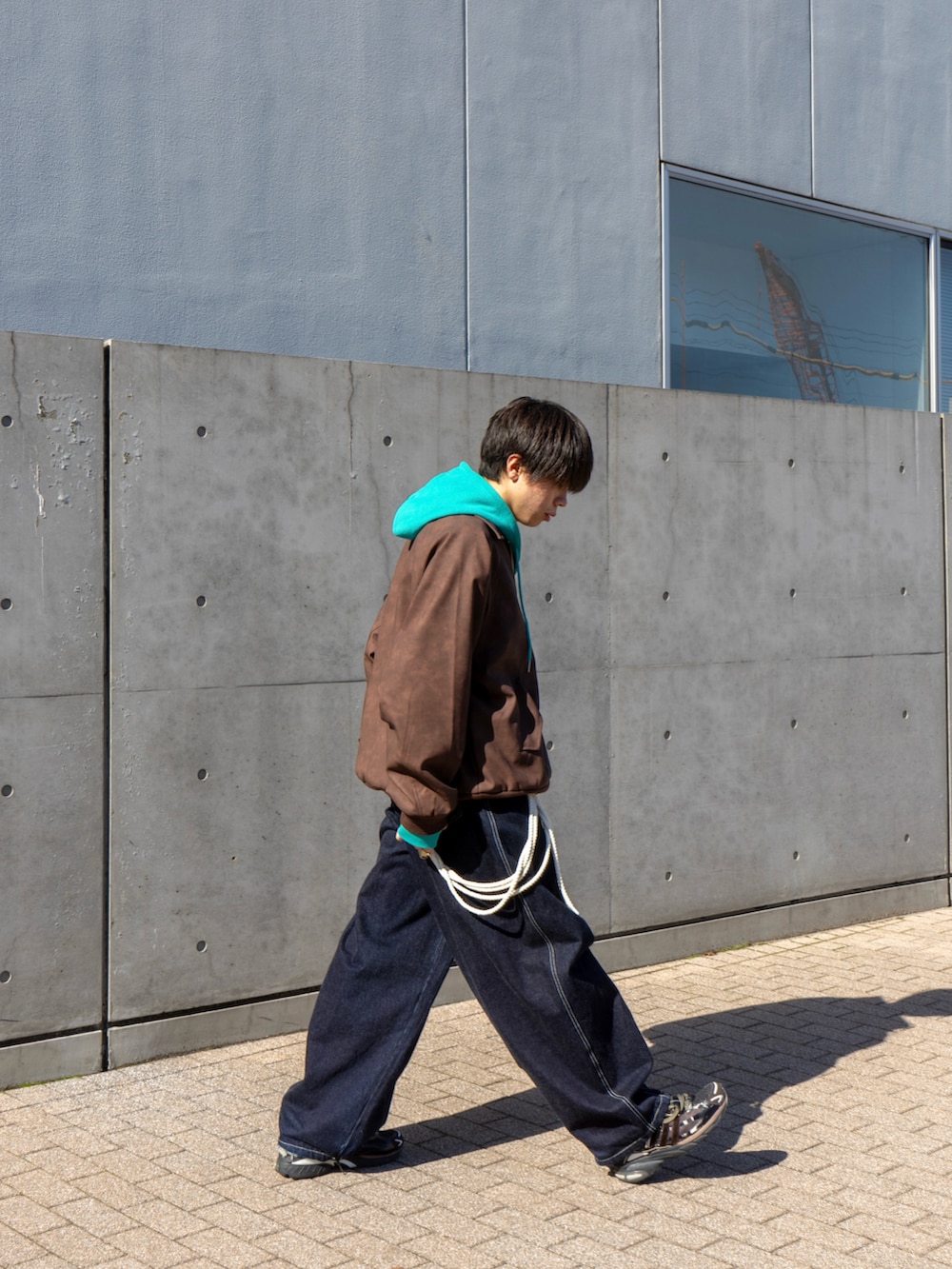 ブラウン系のブルゾン、ブルー系のパーカー、ブルー系のデニムパンツを着用したメンズの秋コーディネートの3枚目の写真