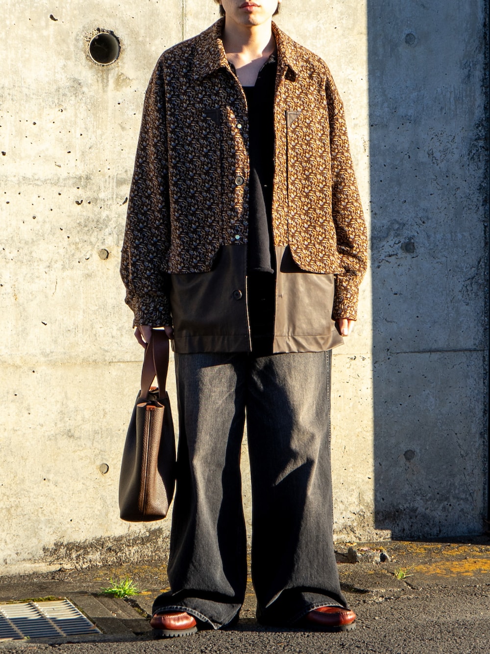 ブラック系のスウェット、ブラウン系のハンドバッグ、ブラック系のデニムパンツを着用したメンズの冬コーディネートの5枚目の写真