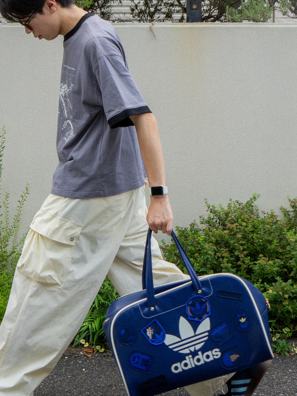 グレー系のTシャツ/カットソー、ブルー系のボストンバッグ、ホワイト系のカーゴパンツを着用したメンズの夏コーディネートの4枚目の写真