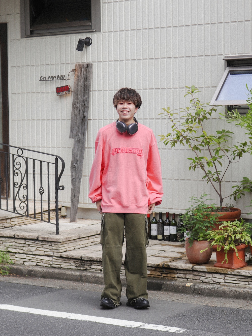 ピンク系のスウェット、グリーン系のカーゴパンツ、ブラック系のスニーカーを着用したメンズの秋コーディネートの3枚目の写真