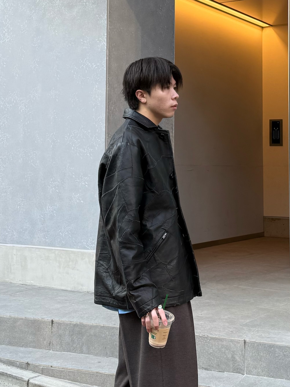 ブラック系のジャケット/アウター、ブルー系のシャツ/ブラウス、ブラウン系のスラックスを着用したメンズの春コーディネートの2枚目の写真