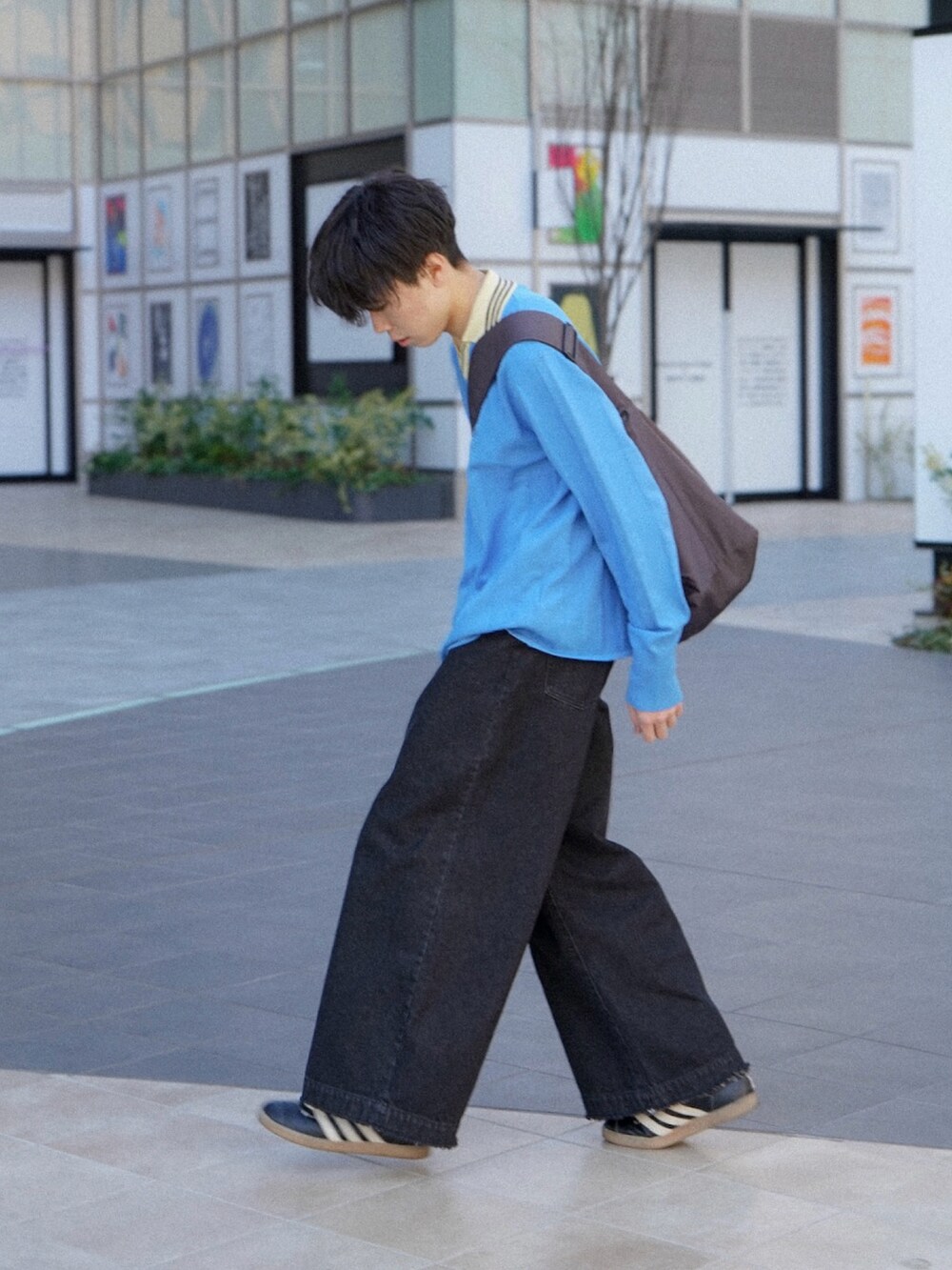 ブルー系のニット/セーター、ブラック系のデニムパンツ、グレー系のショルダーバッグを着用したメンズの冬コーディネートの2枚目の写真