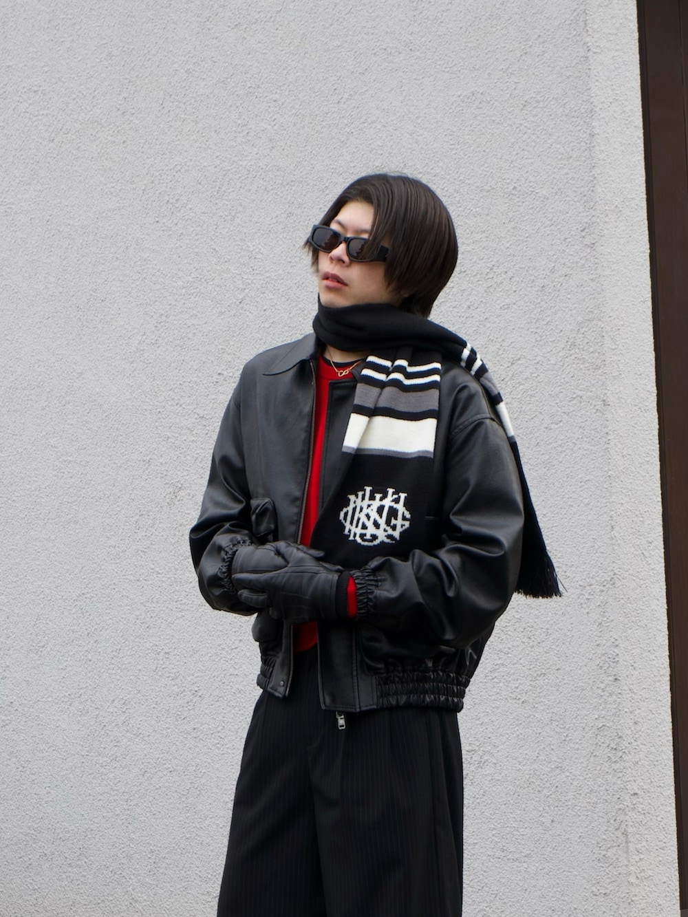 ブラック系のブルゾン、レッド系のニット/セーター、ブラック系のスラックスを着用したメンズの冬コーディネートの4枚目の写真