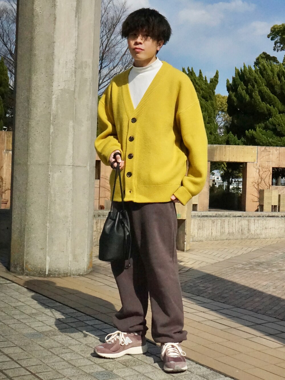 イエロー系のカーディガン/ボレロ、グレー系のスウェットパンツ、ブラック系のショルダーバッグを着用したメンズの春コーディネートの2枚目の写真