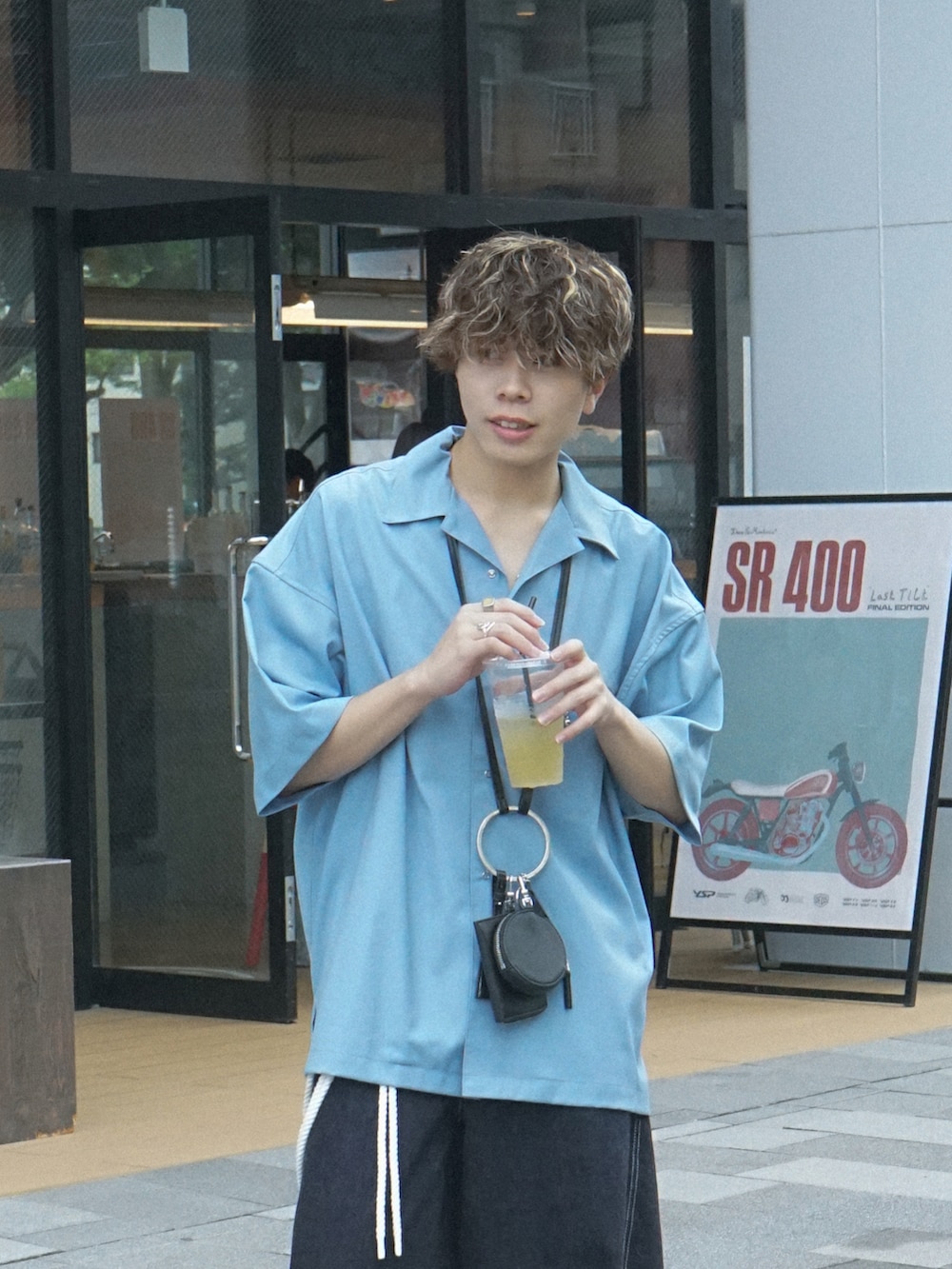 ブルー系のデニムパンツ、ブラック系のショルダーバッグ、ブラック系のサンダルを着用したメンズの夏コーディネートの4枚目の写真