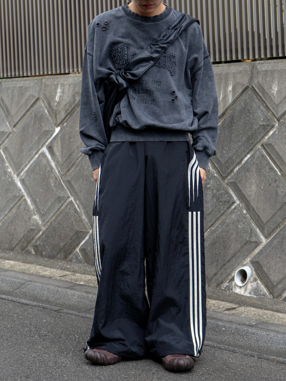 グレー系のスウェット、ブラック系のショルダーバッグ、ブラック系のスウェットパンツを着用したメンズの秋コーディネートの5枚目の写真