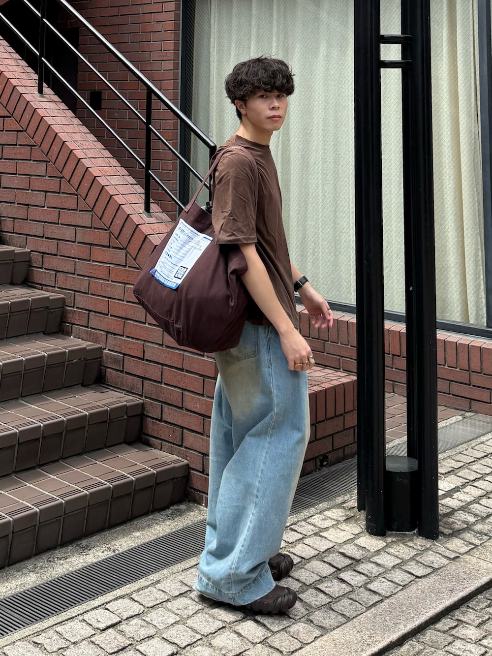 ブラウン系のTシャツ/カットソー、ブルー系のデニムパンツ、ブラウン系のトートバッグを着用したメンズの夏コーディネートの2枚目の写真