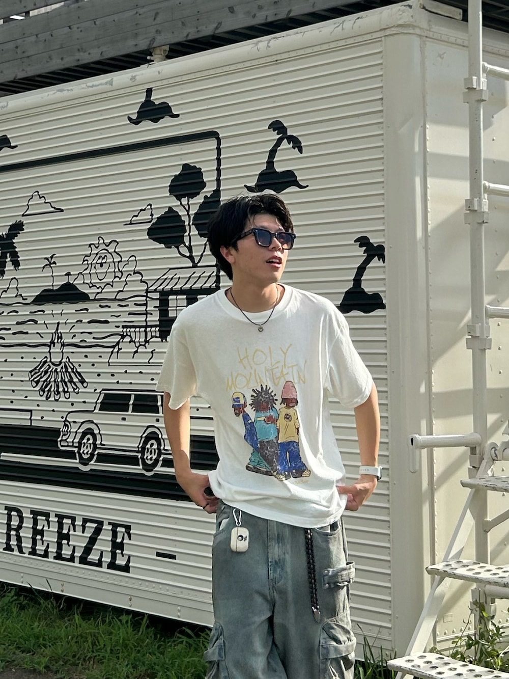 ホワイト系のTシャツ/カットソー、ブルー系のデニムパンツ、ブラック系のサンダルを着用したメンズの夏コーディネートの4枚目の写真