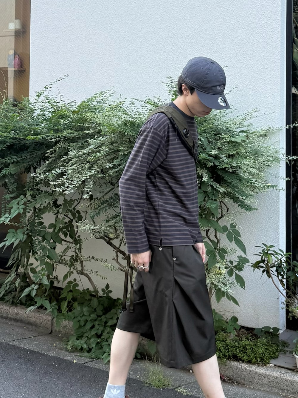 グレー系のTシャツ/カットソー、グリーン系のバックパック/リュック、グリーン系のスラックスを着用したメンズの秋コーディネートの3枚目の写真