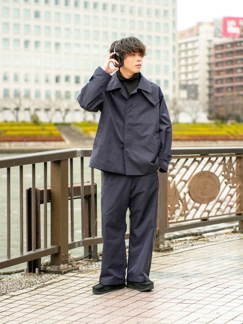 ブラック系のステンカラーコート、ブラック系のその他パンツ、ブラック系のその他シューズを着用したメンズの冬コーディネートの2枚目の写真