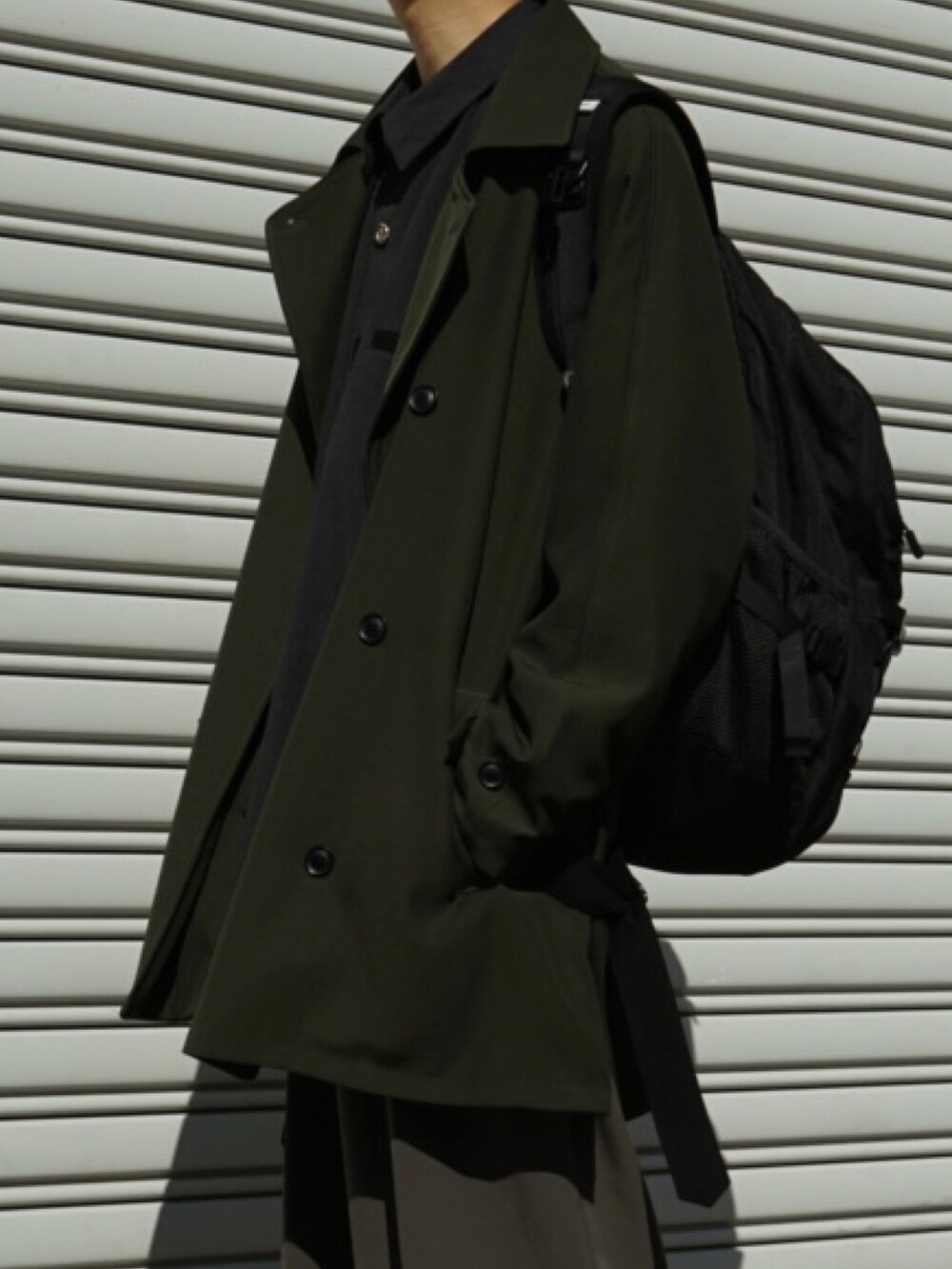 グリーン系のピーコート、ブラック系のバックパック/リュック、グレー系のシャツ/ブラウスを着用したメンズの冬コーディネートの3枚目の写真