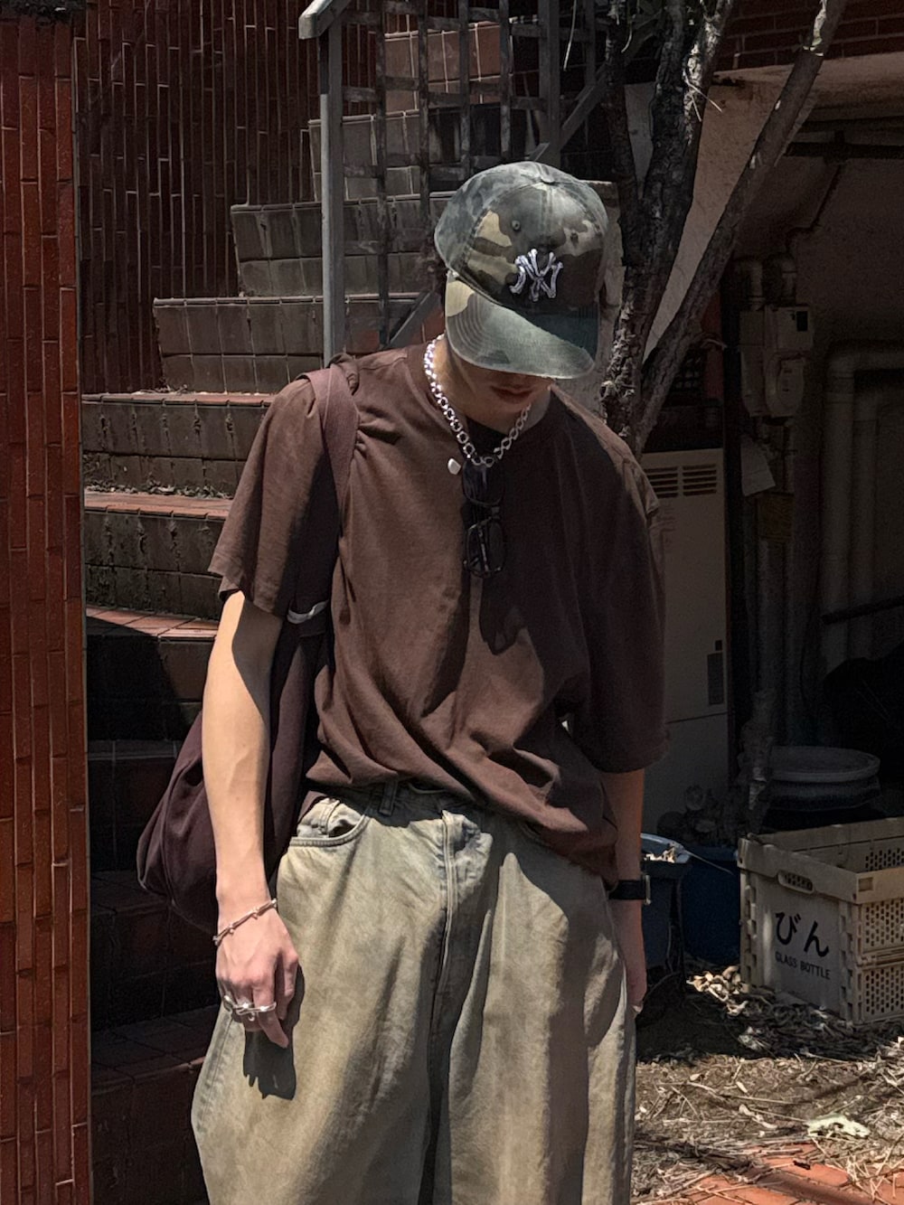 ブラウン系のTシャツ/カットソー、ブラウン系のトートバッグ、ブルー系のデニムパンツを着用したメンズの夏コーディネートの2枚目の写真