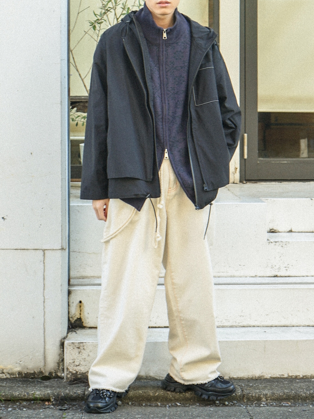 ブラック系のマウンテンパーカー、パープル系のニット/セーター、ブラック系のデニムパンツを着用したメンズの冬コーディネートの5枚目の写真