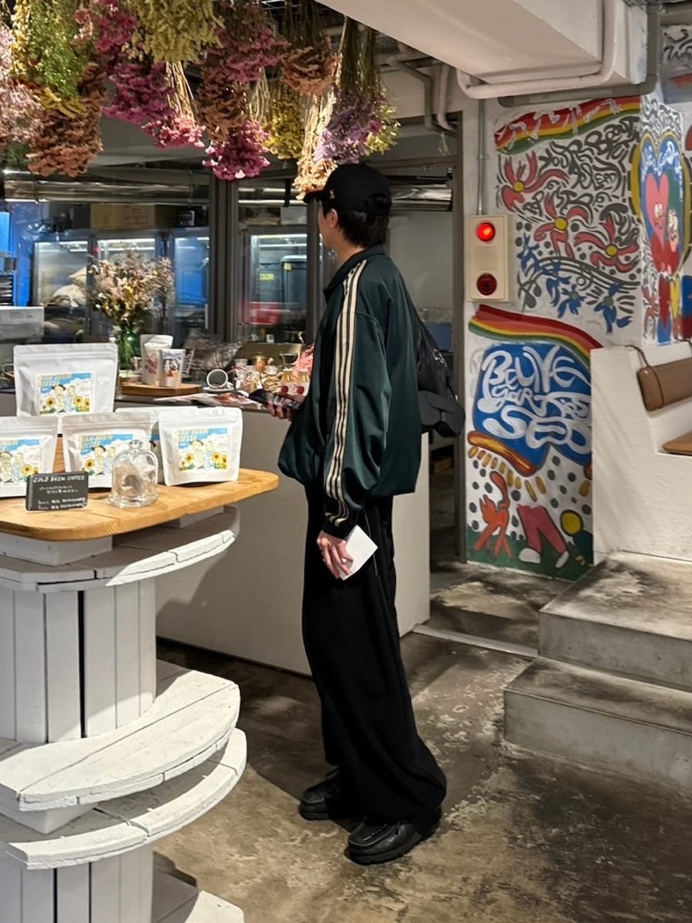 グリーン系のジャージ、ブラック系のスウェットパンツ、ブラック系のブーツを着用したメンズの夏コーディネートの2枚目の写真