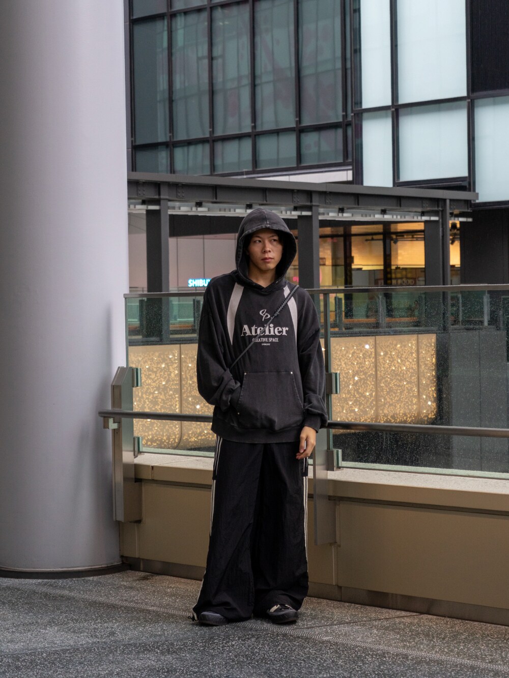 ブラック系のパーカー、ブラック系のスウェットパンツ、ブラウン系のショルダーバッグを着用したメンズの秋コーディネートの3枚目の写真