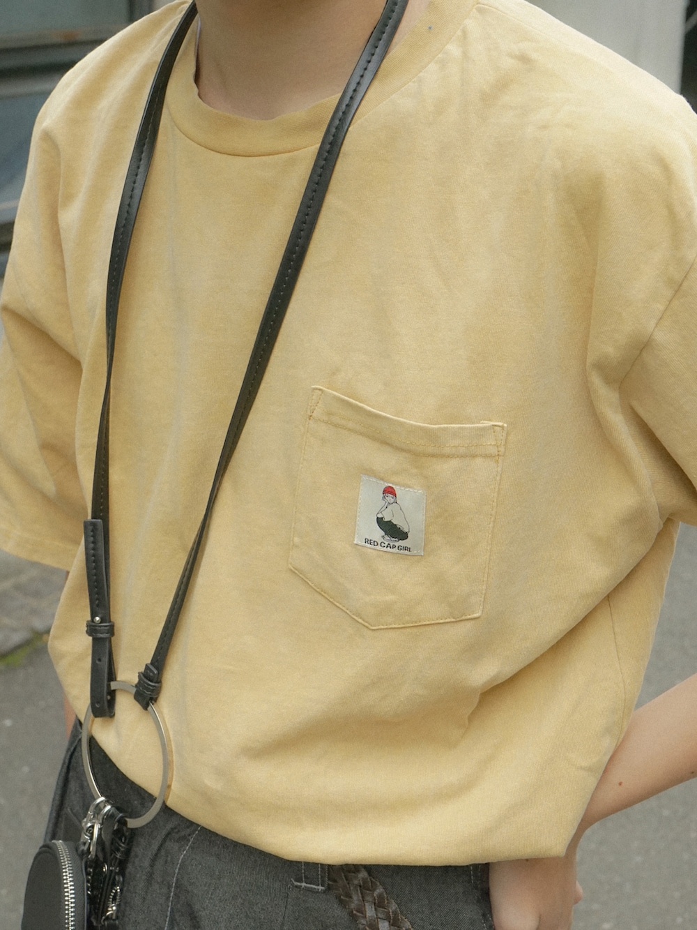 イエロー系のTシャツ/カットソー、グレー系のデニムパンツ、ブラック系のショルダーバッグを着用したメンズの春コーディネートの4枚目の写真