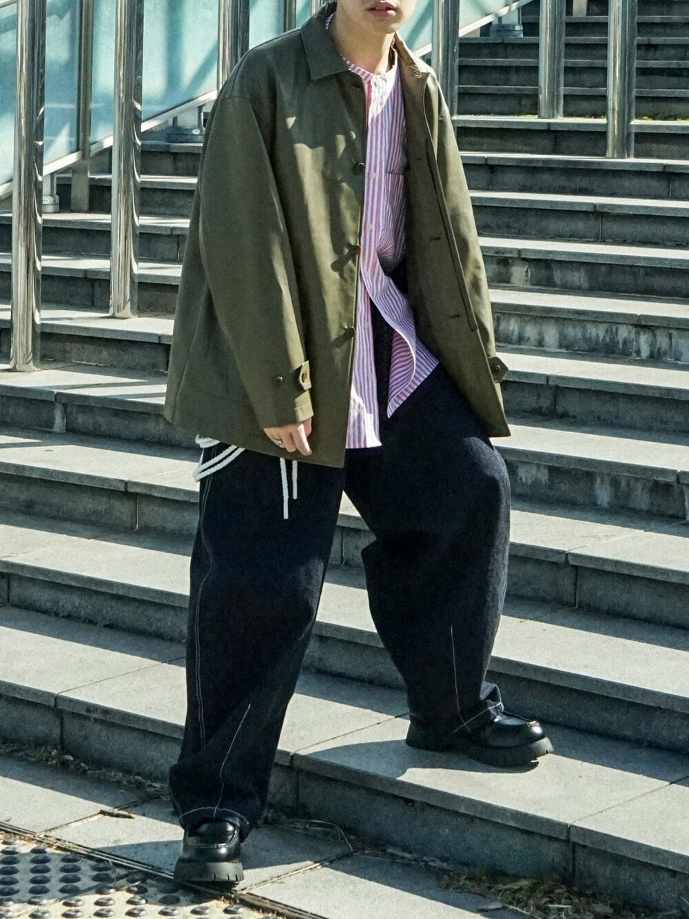 グリーン系のカバーオール、レッド系のシャツ/ブラウス、ブルー系のデニムパンツを着用したメンズの春コーディネートの5枚目の写真