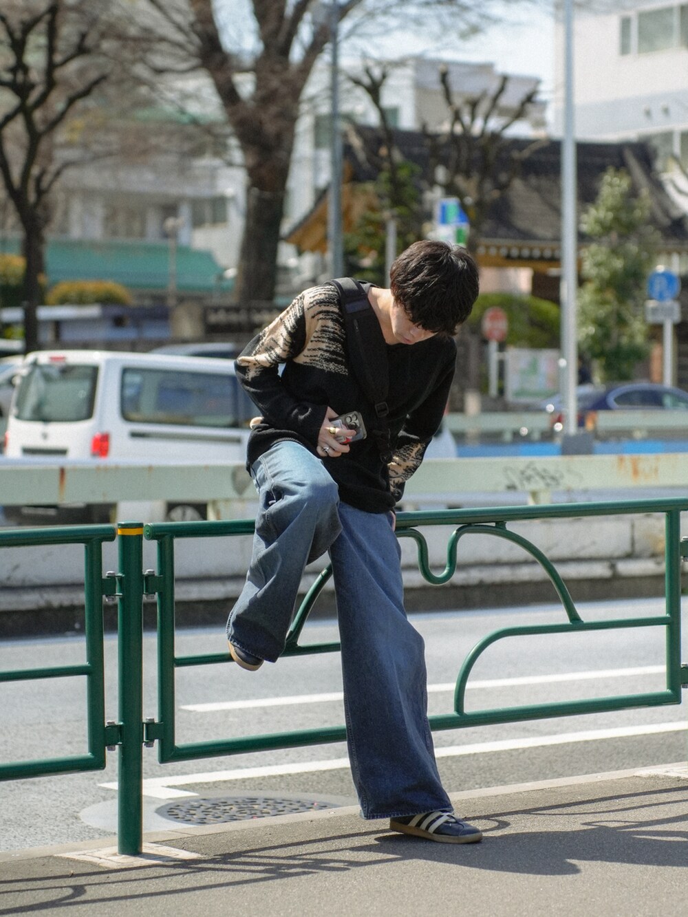 ブラック系のニット/セーター、ブラック系のショルダーバッグ、ブルー系のデニムパンツを着用したメンズの春コーディネートの3枚目の写真