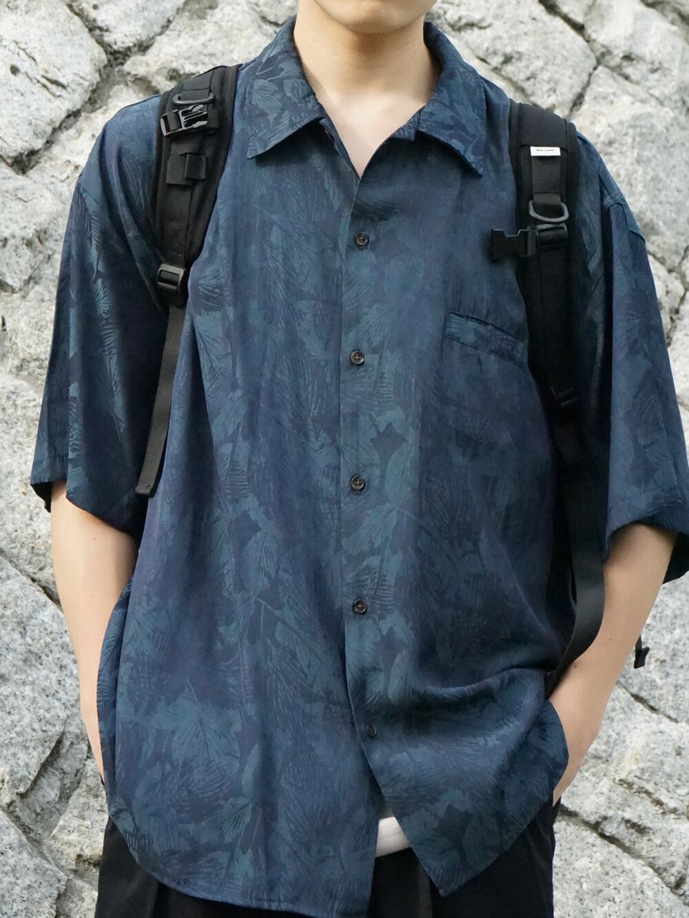 グリーン系のシャツ/ブラウス、グレー系のタンクトップ、ブラック系のバックパック/リュックを着用したメンズの春コーディネートの4枚目の写真