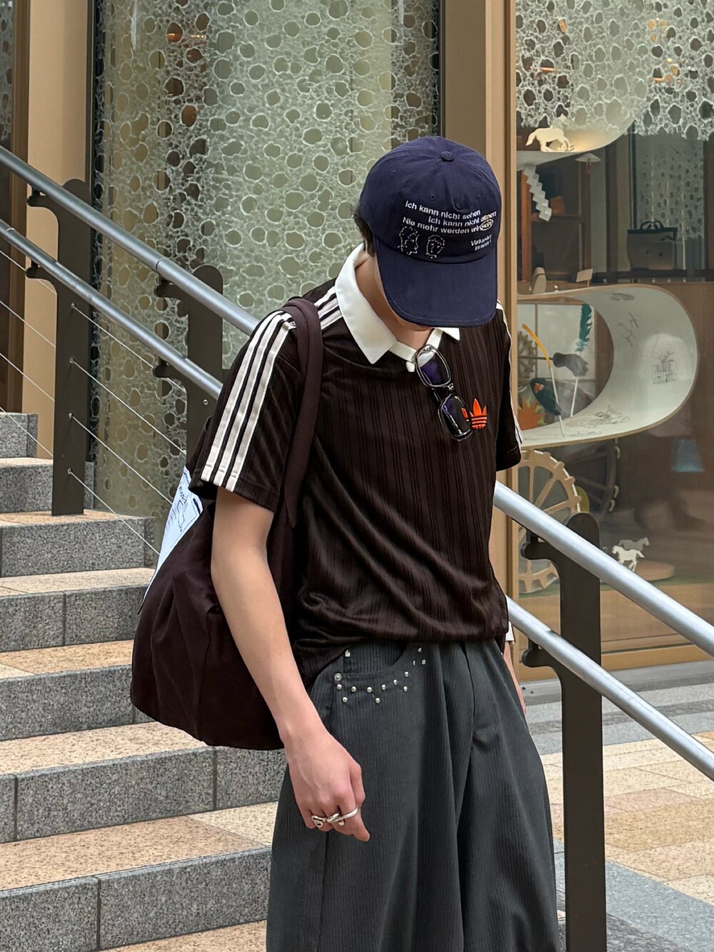 ブラウン系のTシャツ/カットソー、グレー系のスラックス、ブラウン系のトートバッグを着用したメンズの夏コーディネートの4枚目の写真