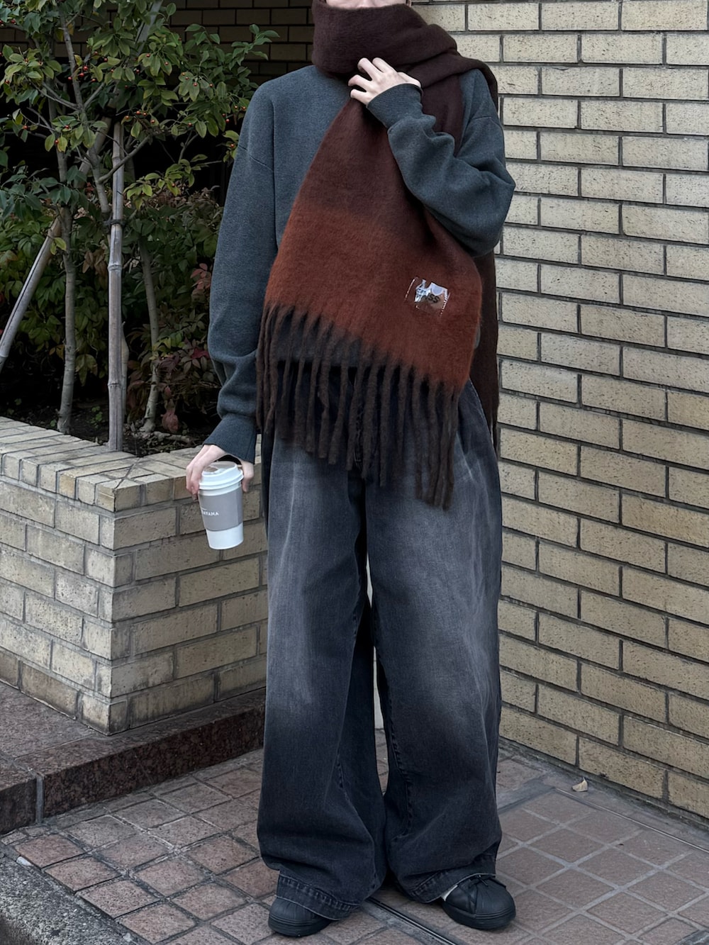 グレー系のニット/セーター、ブラック系のデニムパンツ、ブラック系のスニーカーを着用したメンズの冬コーディネートの4枚目の写真