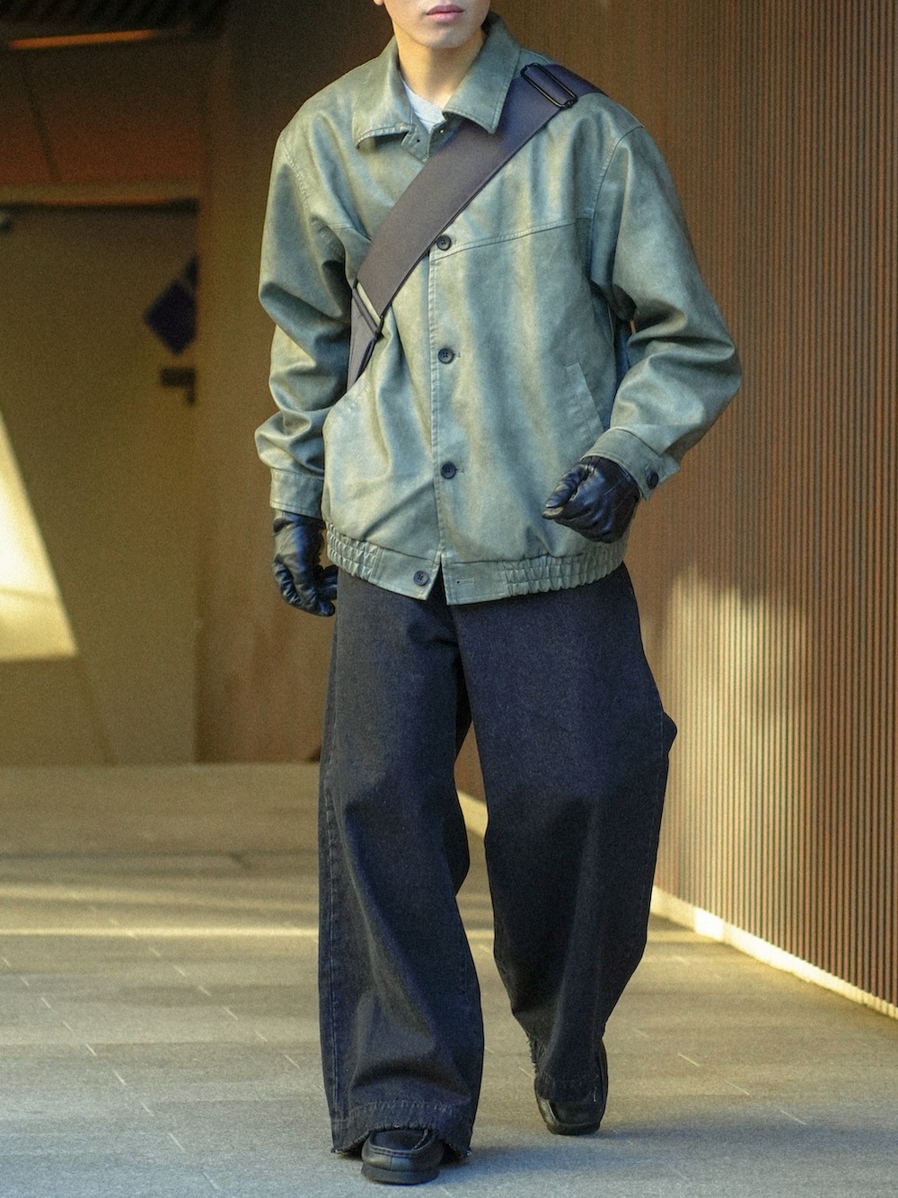 グレー系のブルゾン、ブラック系のデニムパンツ、グレー系のショルダーバッグを着用したメンズの冬コーディネートの5枚目の写真