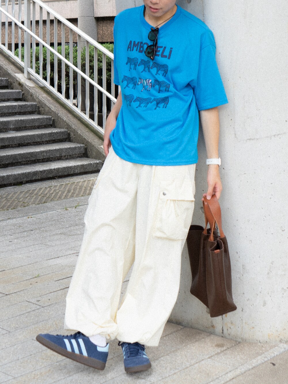 ブルー系のTシャツ/カットソー、ホワイト系のカーゴパンツ、ブラウン系のハンドバッグを着用したメンズの夏コーディネートの3枚目の写真