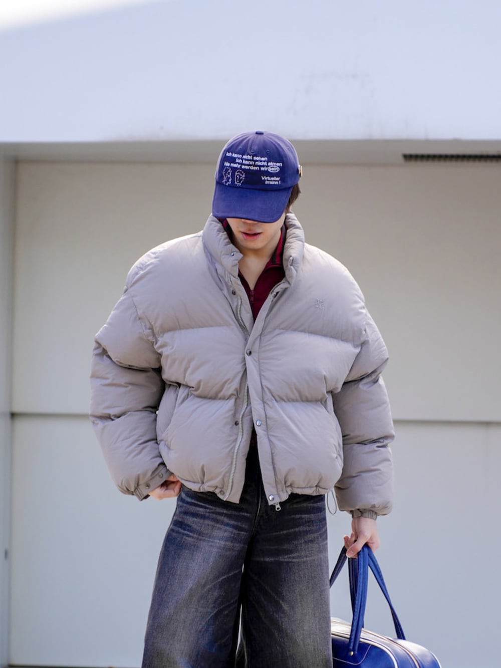 グレー系のダウンジャケット/コート、レッド系のその他トップス、ブラック系のデニムパンツを着用したメンズの秋コーディネートの4枚目の写真