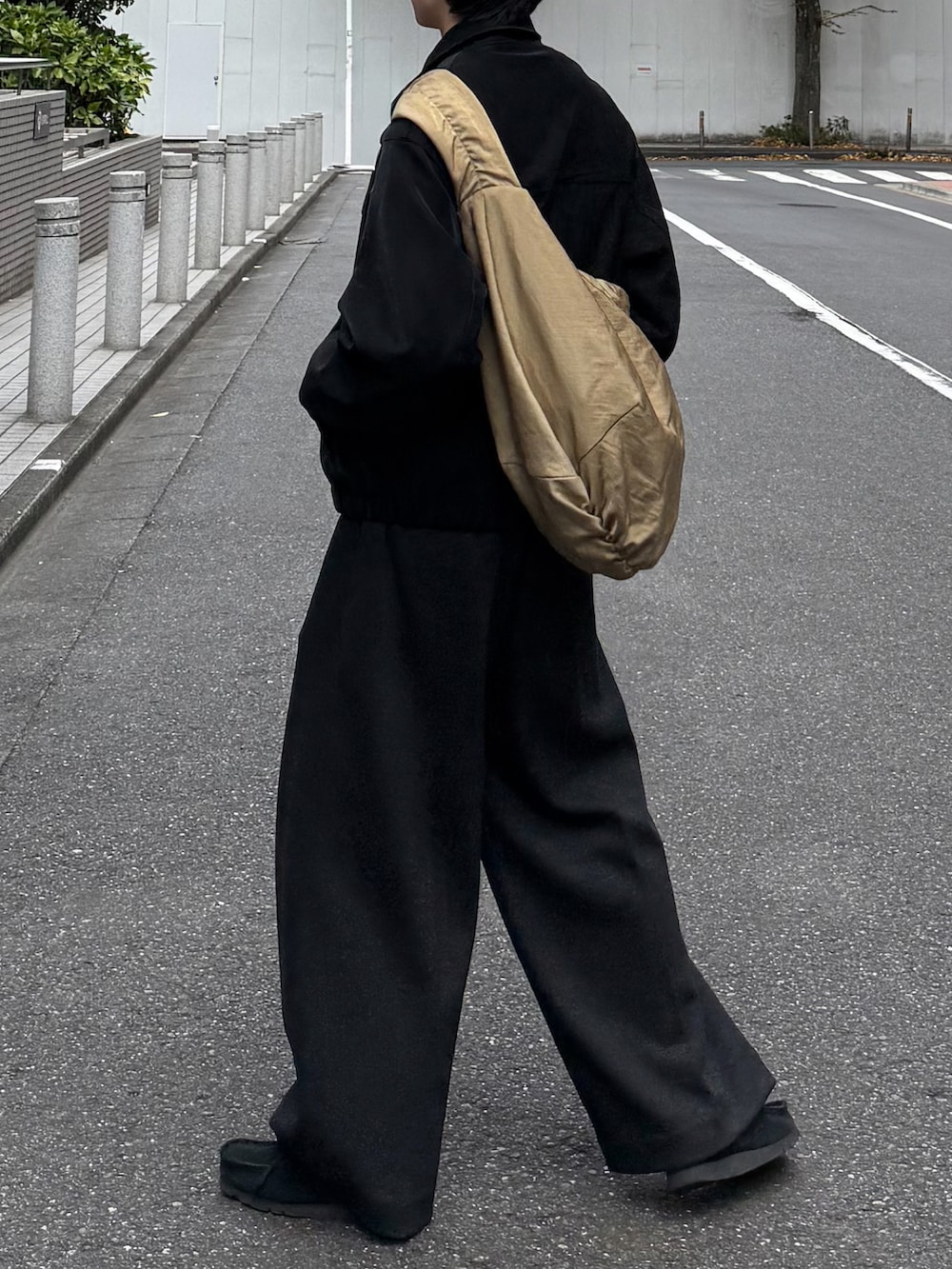 ブラック系のブルゾン、グレー系のスラックス、ベージュ系のショルダーバッグを着用したメンズの冬コーディネートの4枚目の写真