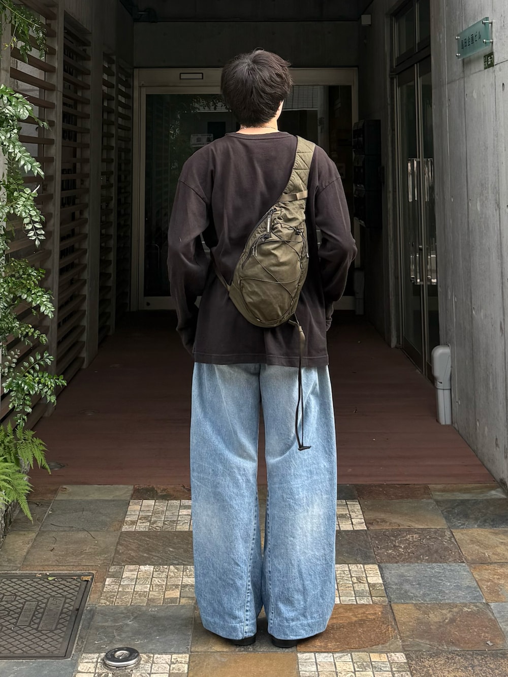 ブラック系のTシャツ/カットソー、ブルー系のデニムパンツ、グリーン系のバックパック/リュックを着用したメンズの夏コーディネートの3枚目の写真