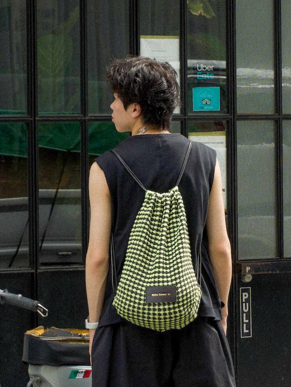 ブラック系のタンクトップ、ブラック系のスラックス、イエロー系のエコバッグ/サブバッグを着用したメンズの夏コーディネートの4枚目の写真