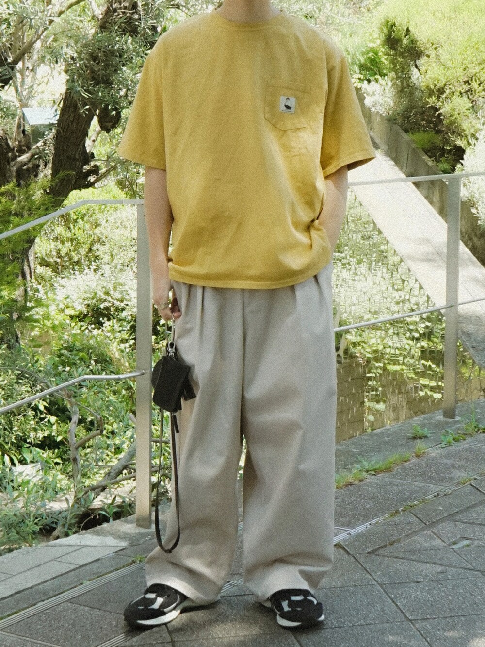 イエロー系のTシャツ/カットソー、ベージュ系のその他パンツ、ブラック系のショルダーバッグを着用したメンズの春コーディネートの5枚目の写真